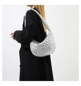 Detail of silver metallic quilted hobo bag featuring large diamond stitching and wide strap
