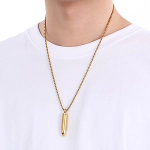 Close-up of a minimalist golden bullet pendant necklace worn by a male model on a white tee