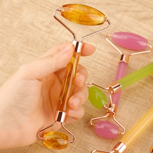 Close-up of dual-head face roller and heart-shaped gua sha board in pink jade finish