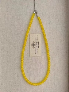 Detailed close-up of yellow chalcedony beaded necklace with silver metal clasp on fabric