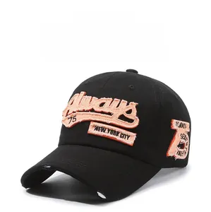 Detailed close-up of vintage black denim baseball cap with orange 3D embroidery and distressed holes