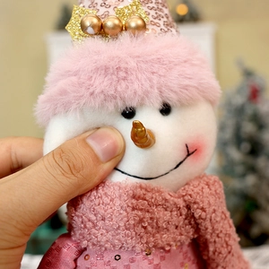 Plush pink Christmas snowman doll with sequins and knit details in festive holiday setting