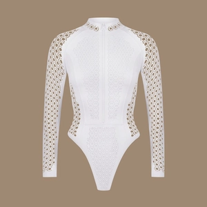 Detail of white long-sleeved bodysuit featuring laser-cut geometric patterns and front zipper
