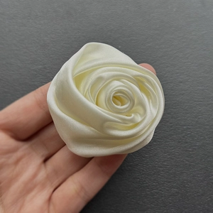 Detail of handmade cream satin rose brooch with elegant 3D folded petals texture