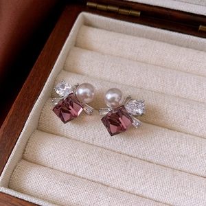 Detailed shot of square purple crystal earrings with pearls in a wooden jewelry box