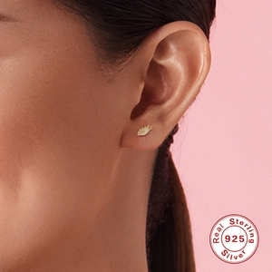 Golden S925 sterling silver leaf ear studs with sparkling zircon worn by a model