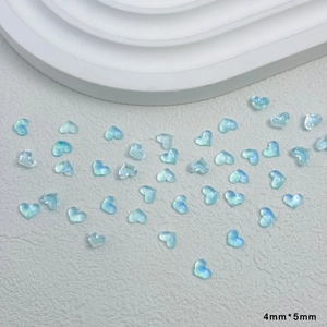 Makroaufnahme von 4mm x 5mm blauen transparenten Herz-Nagelkunst-Anhängern aus Harz