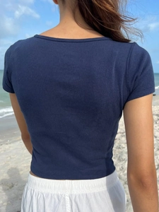 Detail of navy blue ribbed knit T-shirt back view on a model at the beach