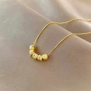 Nahaufnahme einer Goldkette mit fünf mattierten, facettierten Perlen an einer feinen Kette