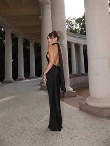 Elegant black backless satin maxi dress with halter tie detail in classical stone corridor