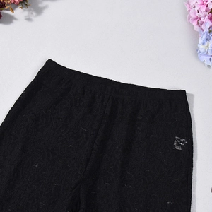 Detail shot of black lace pants with intricate floral patterns and elastic waistband