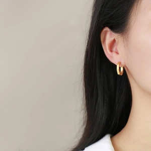 Minimalist gold-plated octagonal hoop earrings featuring geometric faceted surface on model
