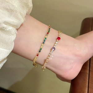 Detail of gold-plated bracelets featuring multicolored zircons worn on the wrist
