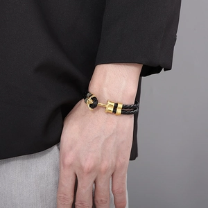 Close-up of double-layer black braided leather bracelet with golden anchor clasp
