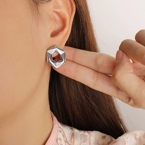 Close-up of geometric hexagonal hollow stud earrings in polished silver metal