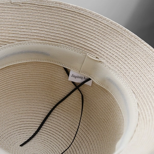 Interior detail of a woven straw sun hat featuring adjustable chin strap and sweatband