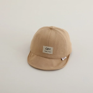Detailed close-up of khaki cotton baby baseball cap with soft brim and square letter patch
