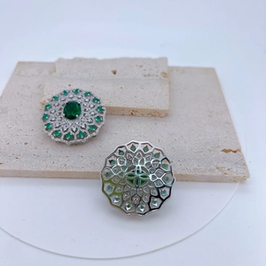 Detail of silver plated copper pendant with green gemstones and zircon settings