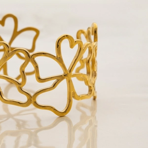 Detailed view of hollow flower and heart patterns on 18K gold plated stainless steel cuff