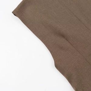 Gros plan sur la texture du tissu marron mélangé et coutures précises de la robe