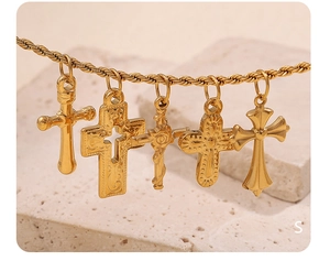 Detail of five golden cross pendants with intricate engravings on natural white stone