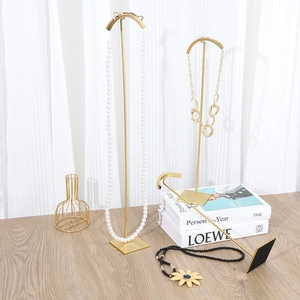 Golden metal jewelry display stand with curved hooks and square base for necklaces