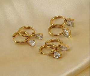 Detail of six gold hoop earrings with teardrop, square and heart crystal charms on silk