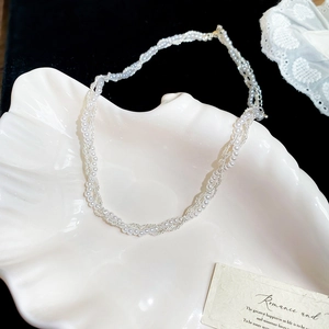 Detailed view of triple-layered pearl and silver chain necklace on a shell plate