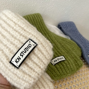 Detailed close-up of ribbed knit winter headbands in cream, green and blue colors