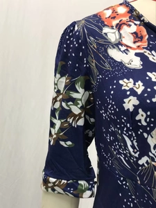 Détail de robe fleurie bleu marine avec col en V, manches bouffantes et maille fine