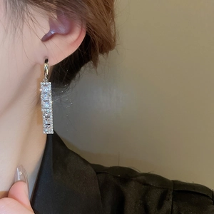 Detail of silver drop earrings with faceted zircon stones worn by a model in close-up