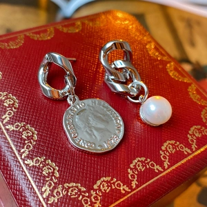 Macro detail of asymmetric silver earrings with pearl and Helvetica 1918 coin charms