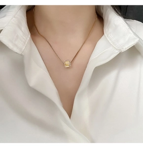 Dettaglio del ciondolo quadrato colorato su collana d'oro in titanio indossata