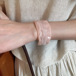 Detail of a wide acrylic bangle with pink marble texture on a model's wrist