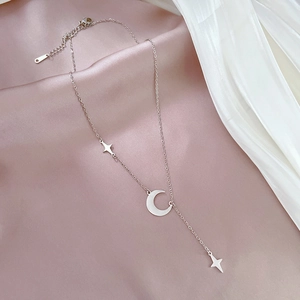 Detailed view of silver star and moon tassel necklace on elegant silk background