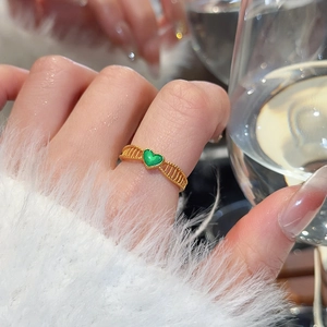 Macro view of gold flower ring with green heart detail and hollow striped texture