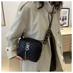 Detail of black quilted crossbody bag with golden CSC charm and geometric wide strap