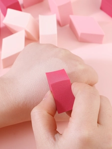 Detail showing non-latex pink wedge makeup sponge applying foundation on hand