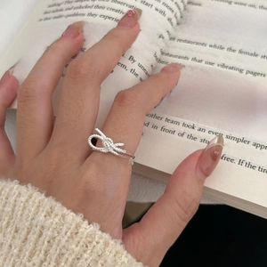 Close-up of a 925 sterling silver bow knot ring on finger with elegant knit texture