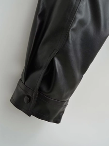 Detail of black PU leather jacket cuff featuring precise stitching and covered button detail