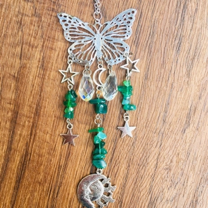 Detail of silver butterfly suncatcher with green natural stones and crystal moon charms