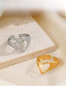 Detailed view of adjustable gold and silver hollow heart rings on a textured stone surface