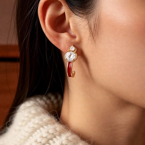 Detailed shot of gold-plated gourd earring with red enamel and zircon on a model