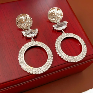 Detailed view of silver hoop earrings with zircon accents on a red wooden jewelry box