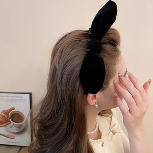 Detail of elegant black velvet bow headband with non-slip teeth worn by a model