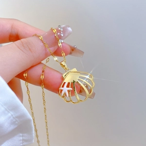 Detail of gold shell pendant necklace with white starfish held by a hand