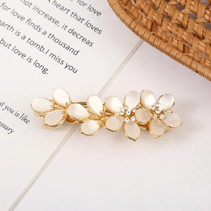 Macro detail of a golden flower hair clip with opal stones on an open book page