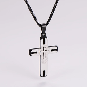 Detailed close-up of a dual-tone black and silver cross pendant with a metal chain