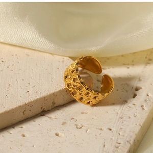 Detailed view of a gold double-layer chain hollow ring on a stone base with silk backdrop