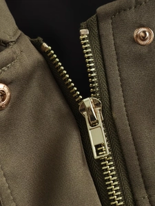 Detailed macro view of gold metal zipper and snap button on olive green bomber jacket